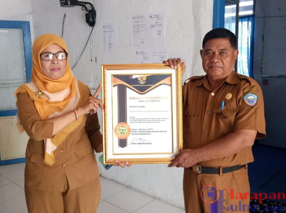 Sekretaris BKPSDM Busel (Kanan) saat menunjukkan Piagam Penghargaan yang diterima dari BKN