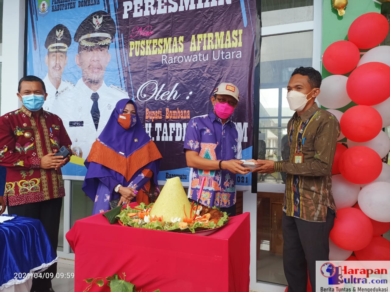 Bupati Bombana, H. Tafdil saat menyerahkan tumpeng kepada Kepala Puskesmas Rarowatu Utara Satar, SKM